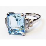 A marked PLAT Art Deco style ring, set with central 5.35ct. emerald cut aquamarine and six