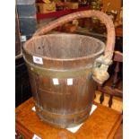 An antique brass bound coopered oak fire bucket with stitched leather clad rope handle