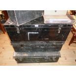 Two black painted tin transit trunks and a footlocker similar