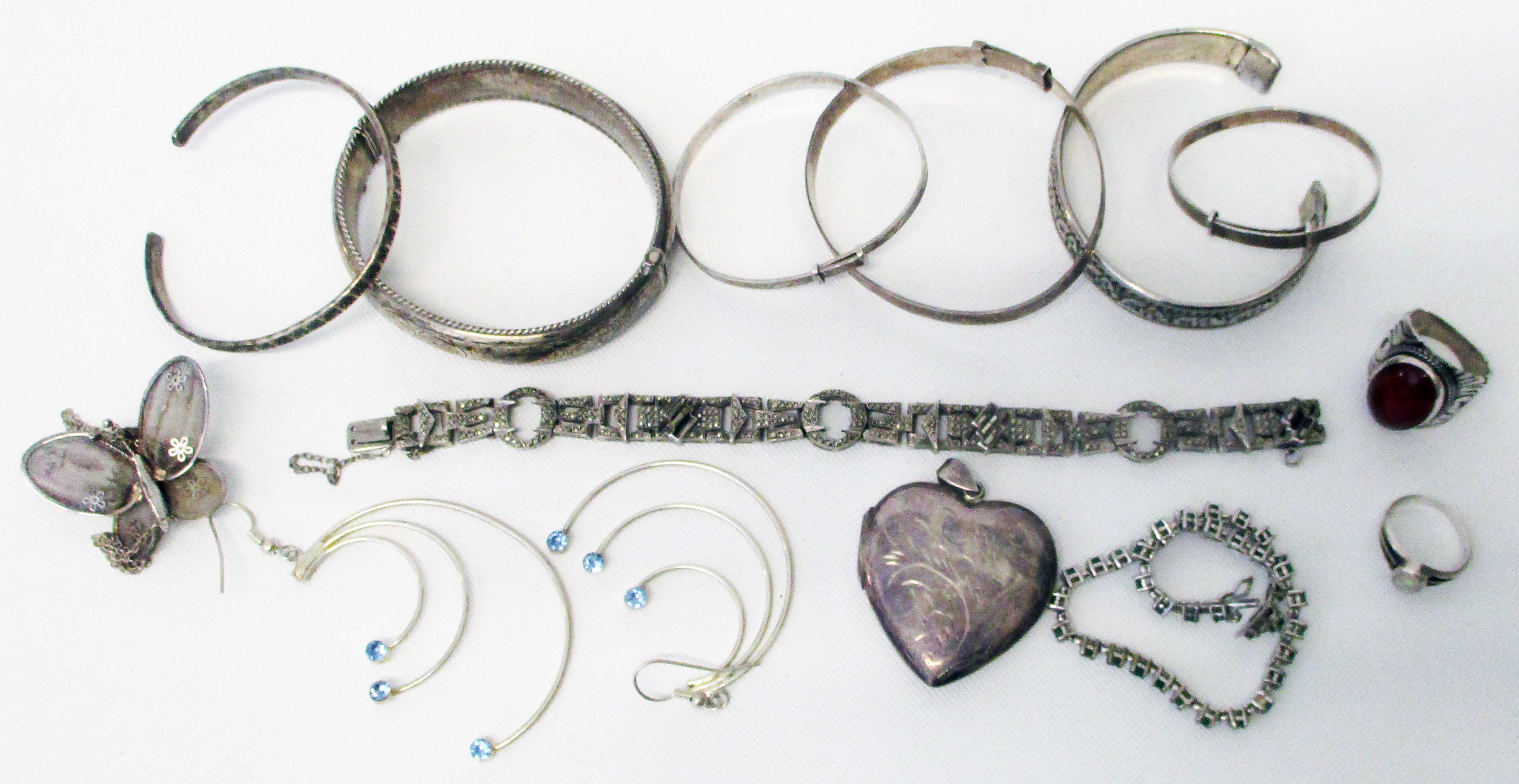 A collection of silver and white metal jewellery including bangles, heart shaped locket,