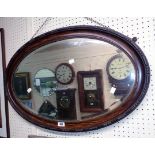 An early 20th Century grained and beaded framed bevelled oval wall mirror