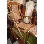 A vintage stained wood folding framed steamer style chair with rattan back and seat panels