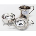 A modern silver tea strainer and stand with hoof pattern feet - sold with a small silver cream jug