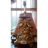 A cast gilt brass table lamp with bacchanalian putti decoration, with shade