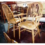 A pair of modern blonde wood wheel back kitchen elbow chairs with solid section seats, set on turned