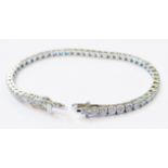 A marked 18k white metal tennis/in line bracelet, each of the links set with an individual brilliant