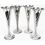 A set of four 7 1/2" silver trumpet vases with shaped rims and spiral decoration set on loaded