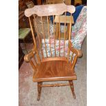 A 20th Century mixed wood high stick back rocking chair with solid laminated seat and ring turned