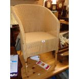 A modern Lloyd Loom tub chair - sold with an oak framed foot stool with fitted floral pattern