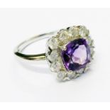 A hallmarked 375 white gold ring, set with central amethyst within a diamond encrusted border