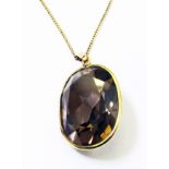 A yellow metal framed oval smokey quartz pendant on 9ct. chain