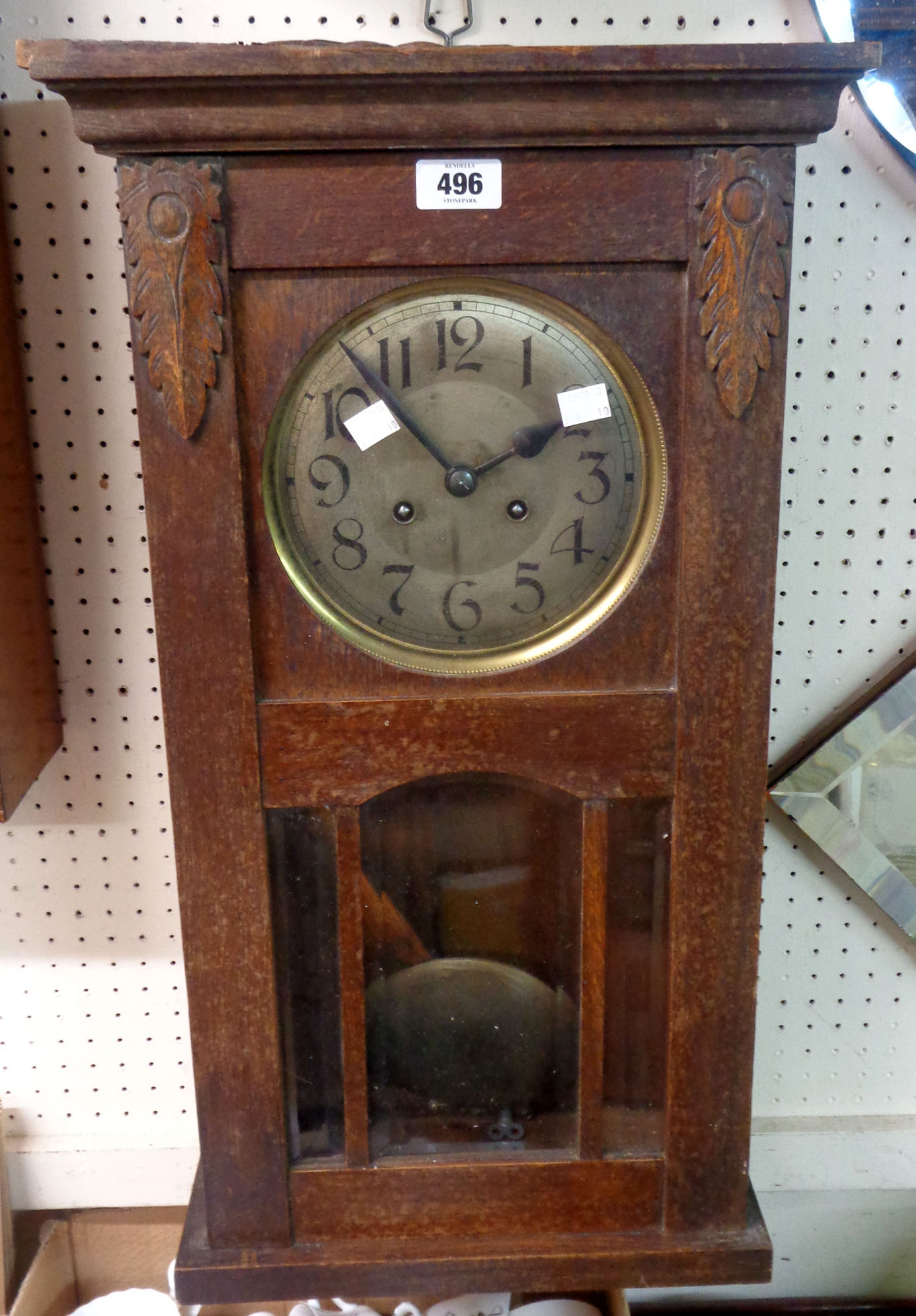 An early 20th Century stained oak cased wall clock with visible pendulum and gong striking