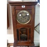 An early 20th Century stained oak cased wall clock with visible pendulum and gong striking