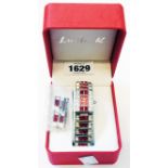 A box Lucie K ornate polished steel wristwatch with red dial and encrusted with red and white