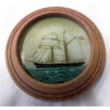 A circular oak framed miniature painting on glass of a British sailing ship with ensign
