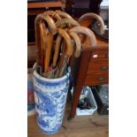 A large ceramic stick stand containing assorted walking canes and umbrellas