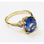 A hallmarked 585 14k gold ring, set with central oval tanzanite and diamond encrusted shoulders