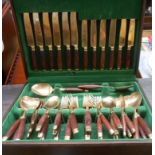 A stained wood canteen containing a six place setting of bronze cutlery with wooden clad handles