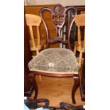 A set of four late Victorian mahogany framed dining chairs with ornate pierced splat backs and