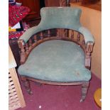 An Edwardian stained oak framed bow elbow chair with spindle decoration and remains of green cord