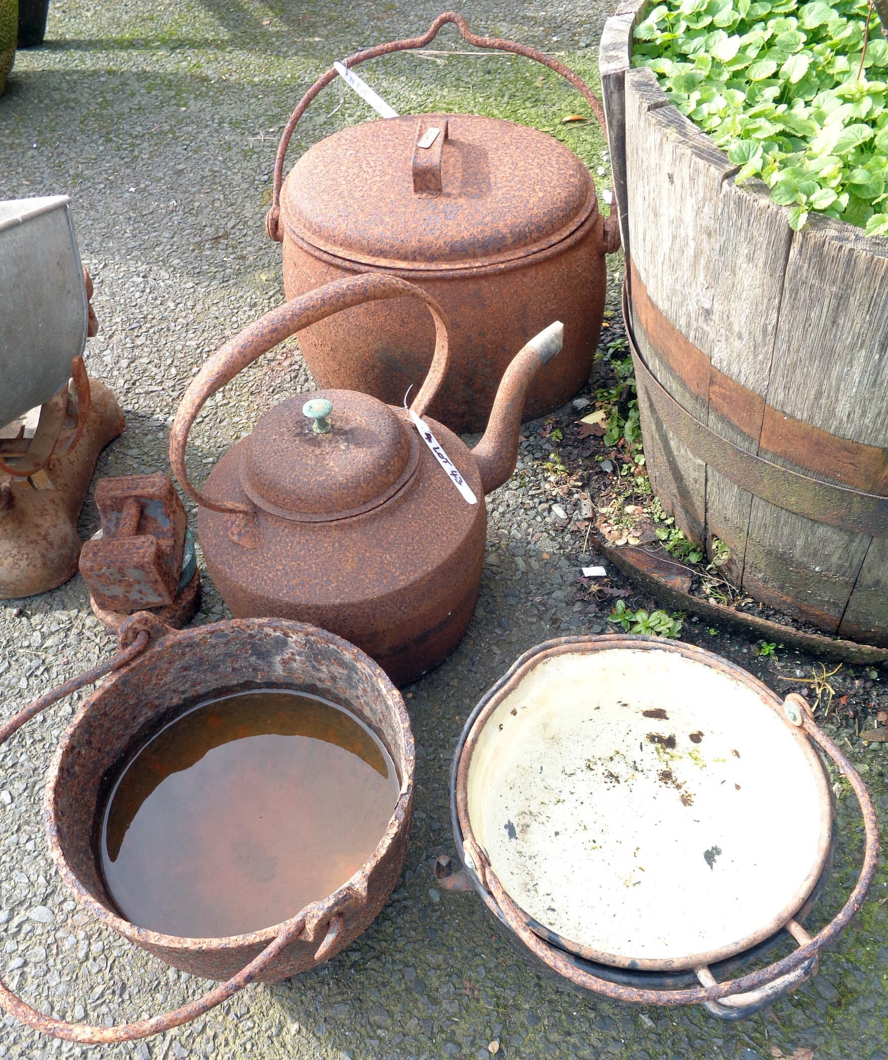 A large cast iron kettle, an oval hanging saucepan with lid and another pot - sold with two iron and