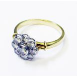 A hallmarked 750 gold flowerhead pattern ring, set with nine diamonds