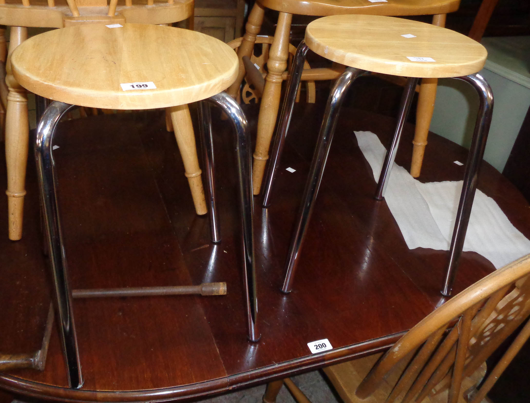 A pair of modern stools with polished blonde wood tops and chrome plated legs