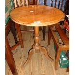 A 18 1/2" diameter waxed pine pedestal table, set on turned pillar and tripod base