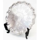 A 12 1/2" diameter silver salver with shaped cast rim, engraved decoration and central initial "