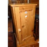 A 15 1/2" waxed pine bedside cabinet enclosed by a panelled door, set on plinth base