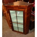 A 30 1/4" antique mahogany wall mounted corner cabinet with shelves enclosed by a glazed panel
