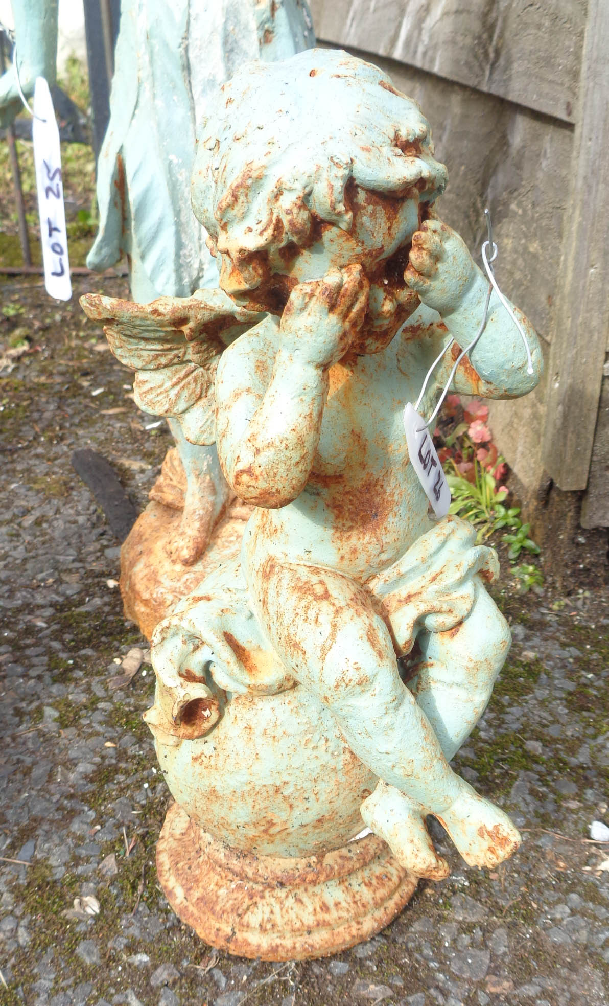 A cast iron garden angel seated on a ball