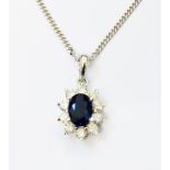 A hallmarked 750 white gold pendant, set with central oval sapphire within a ten stone diamond
