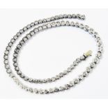 A marked 750 white metal tennis/in line necklace, each of the links with an individual collar set