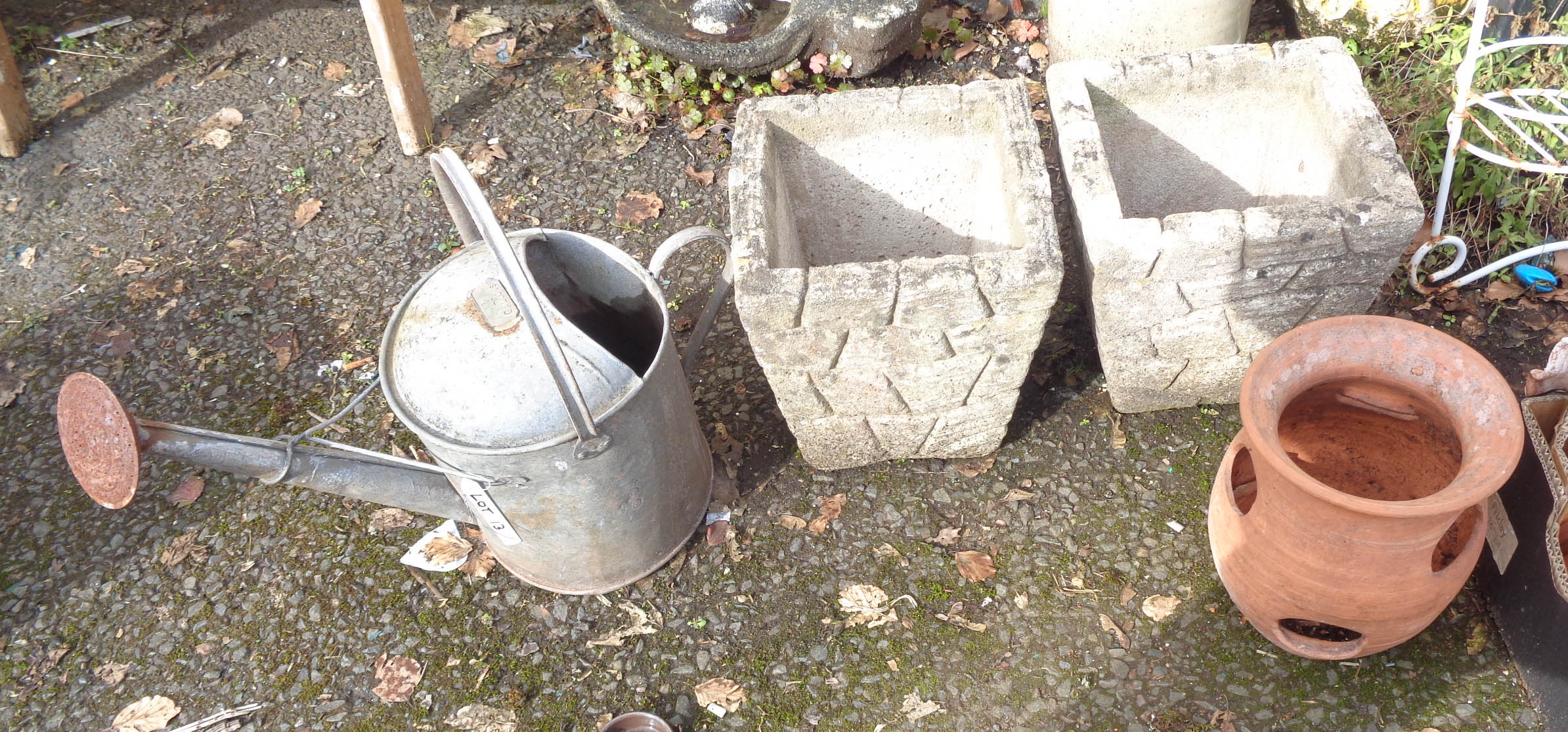 A pair of concrete planters, strawberry pot and vintage watering can