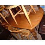 A 5' 2" modern polished pine kitchen table with slightly rounded ends, set on turned legs