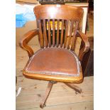 A vintage polished oak framed lath back swivel office elbow chair with studded upholstered seat