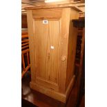 A 15 1/2" waxed pine bedside cabinet enclosed by a panelled door, set on plinth base