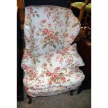 A 20th Century wing back fireside armchair with floral upholstery and cushions, set on cabriole