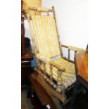 An antique American stained wood framed rocking chair with slung upholstery and turned spindle