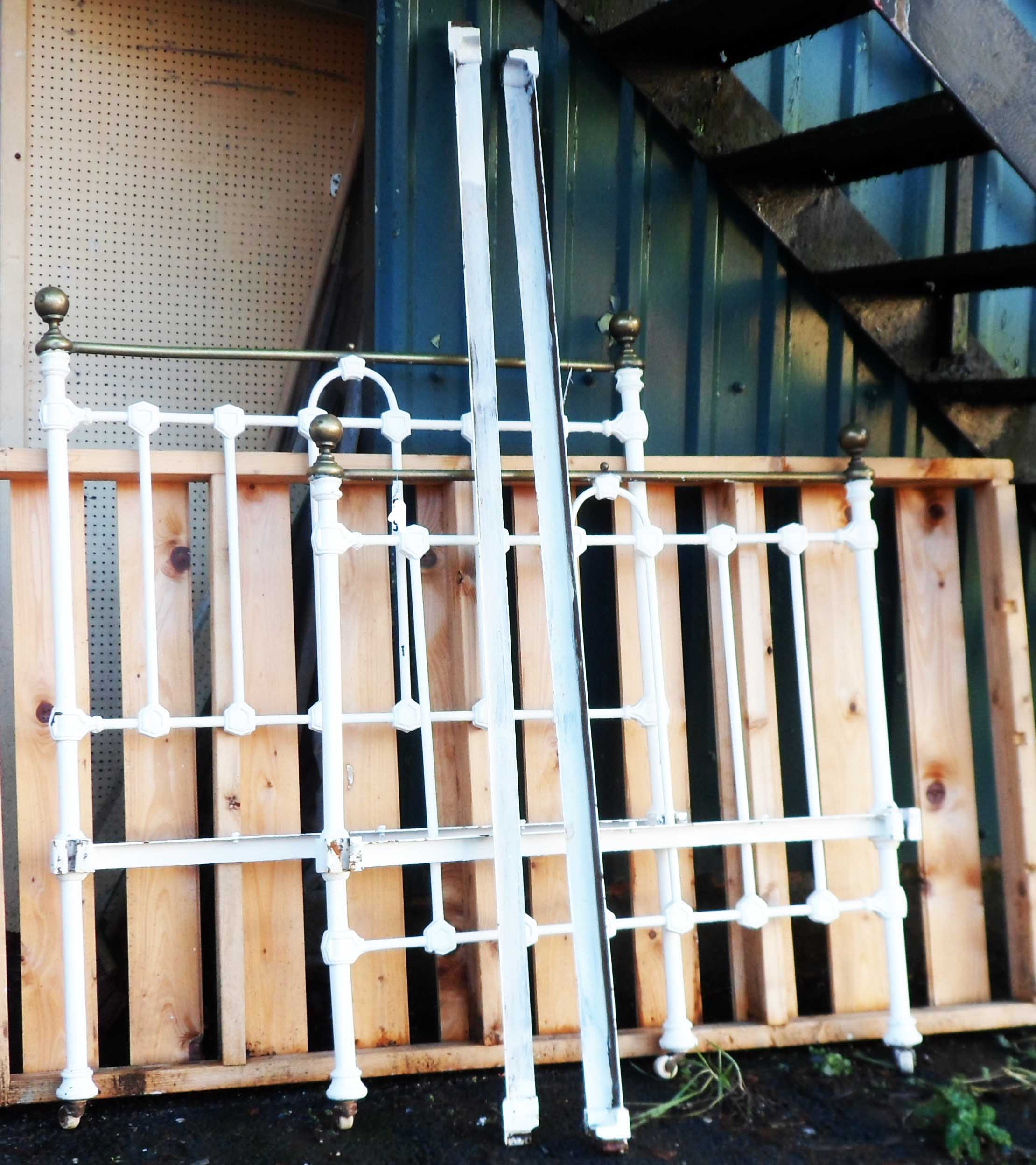 An antique cast iron and brass later painted bedstead, set on white porcelain casters, with later