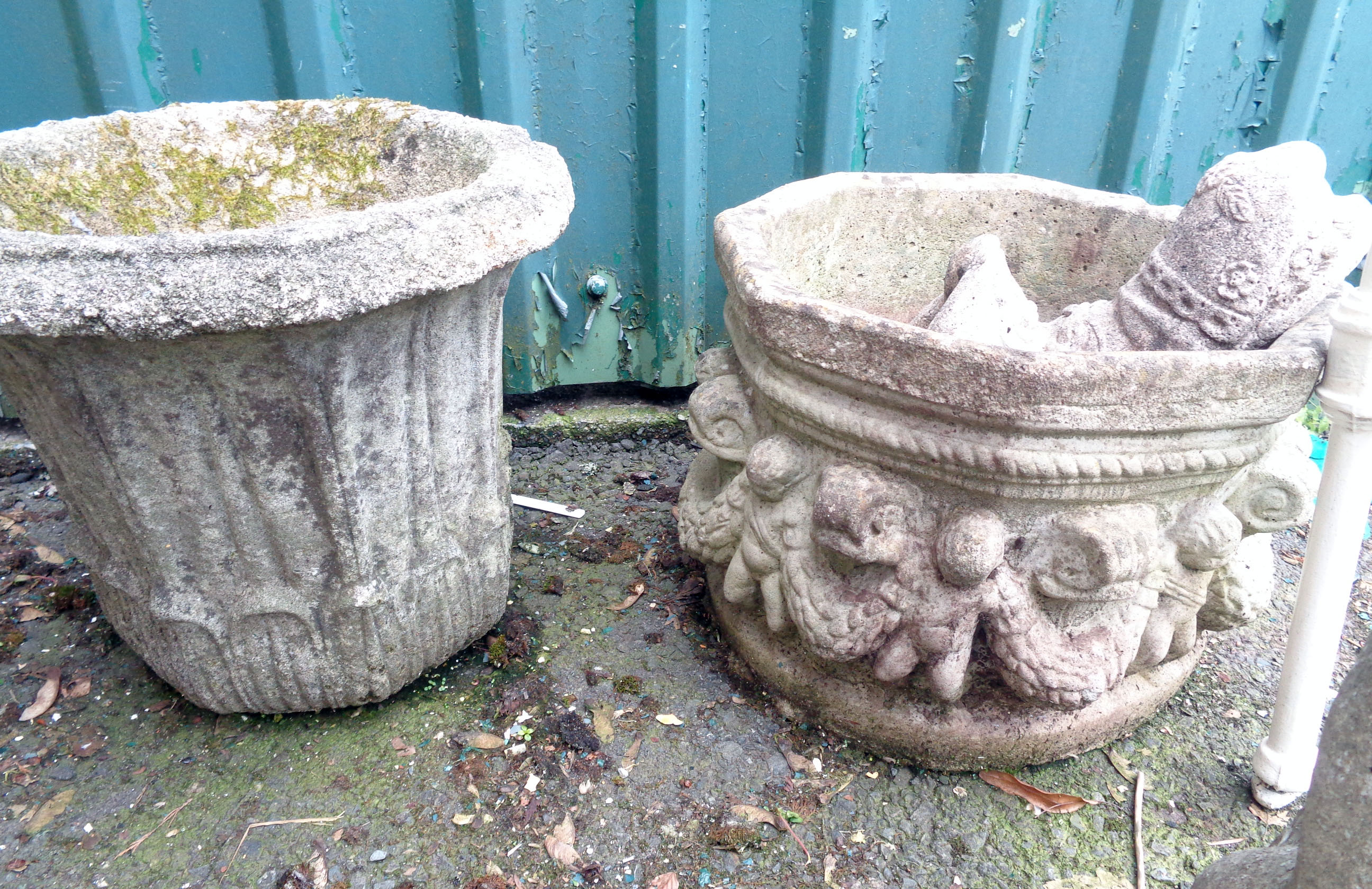 A large concrete garden urn, decorated with putti and swags, another similar and a smaller planter