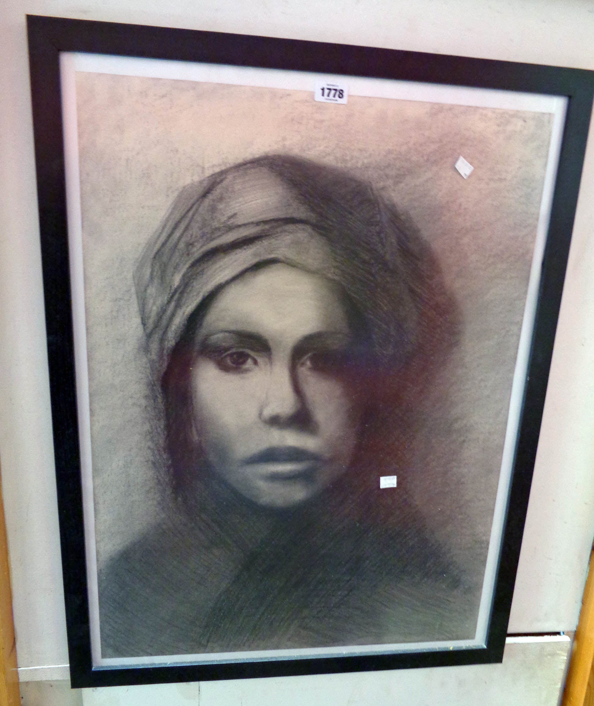 A large framed monochrome charcoal and pencil portrait of a woman wearing a head scarf