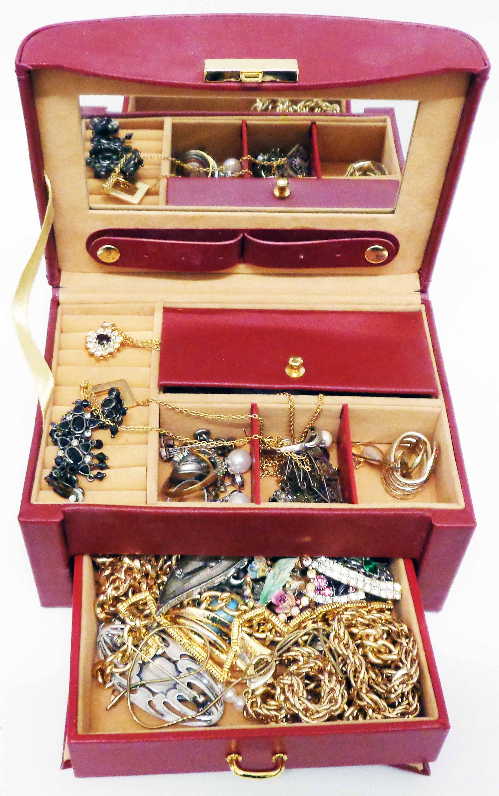 A maroon travelling jewellery case containing a quantity of assorted costume jewellery