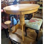 A 29 1/2" diameter modern blonde wood pedestal table, set on turned pillar and quadruple cabriole