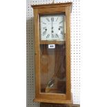 A Knight & Gibbins polished oak cased wall clock with visible pendulum and eight day chiming