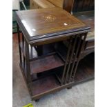 An Edwardian mahogany and strung mixed wood revolving bookcase, set on porcelain castors - some