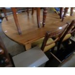 A 5' 2" modern polished pine kitchen table with slightly rounded ends, set on turned legs