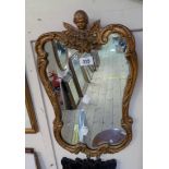 A vintage ornate gilt framed mirror with cherub pediment and shaped plate
