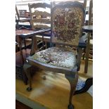 A 20th Century stained walnut framed panel back elbow chair upholstered in floral tapestry, set on